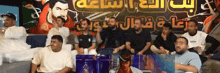 a group of people are sitting in front of a sign that says ' arabic ' on it