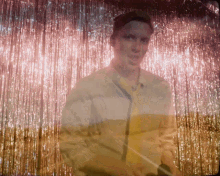 a man in a yellow and white striped jacket is standing in front of a tinsel curtain