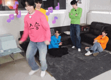 a man in a pink sweater with korean writing on it is dancing in a living room