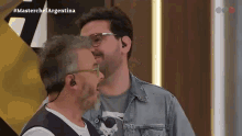 two men are standing next to each other in front of a masterchef argentina logo