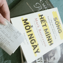 a person is holding a receipt over a book titled het minh