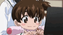 a little girl is smiling while looking at a laptop screen