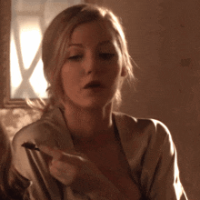 a woman in a robe is holding a piece of food in her hand