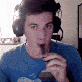 a man wearing headphones and a blue shirt is blowing a cigarette
