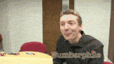 a man sitting at a table with the name numberphile written on the bottom