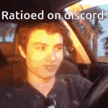 a man is sitting in a car with the words `` ratioed on discord '' written on the bottom .