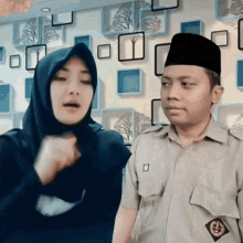 a man and a woman are standing next to each other in front of a wall with squares on it