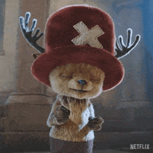 a stuffed animal wearing a red hat with antlers and a cross on it