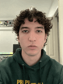 a young man with curly hair is wearing a green hoodie that says pro peace