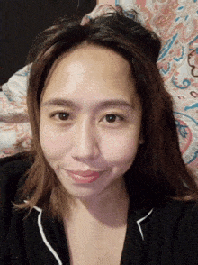 a close up of a woman 's face with a floral blanket in the background