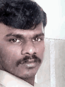 a close up of a man 's face with a mustache looking at the camera .