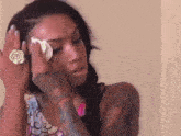 a woman with a tattoo on her arm wipes her eye with a tissue