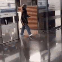a person is walking down a hallway with a reflection of a person on the floor .