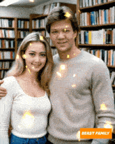 a man and a woman are posing for a picture in a library with a beast family sticker in the corner
