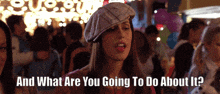 a woman in a plaid hat says " and what are you going to do about it " in front of a crowd