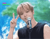 a young man is giving a peace sign in front of a microphone with the show written on the screen behind him
