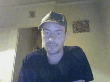 a man wearing a hat and black shirt looks at the camera