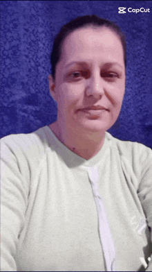 a woman is taking a selfie in front of a blue background and the caption reads " capcut "