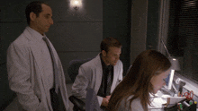 a man in a white coat stands next to a woman in a white shirt