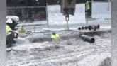 a construction worker is laying in the dirt while a crane is lifting a pipe .