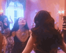 a group of women are dancing in a room with pink lights