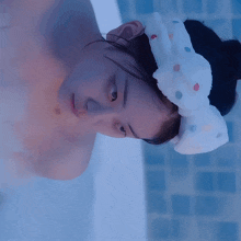 a woman in a bathtub wearing a headband with polka dots