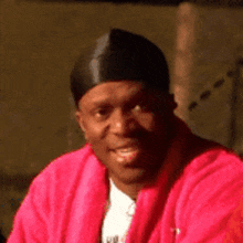 a man is wearing a pink jacket and a black hat .