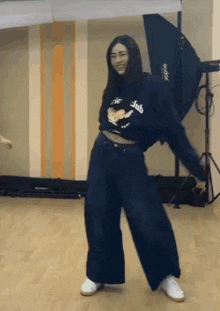a woman is dancing in a room wearing a crop top and wide leg jeans .