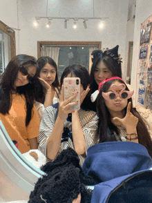 a group of girls are posing for a picture in front of a mirror with one girl wearing a phone case that says hello kitty