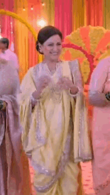 a woman in a yellow saree is standing in front of a group of women .