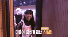 a girl in a white tank top is smiling in a doorway