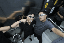 a man wearing sunglasses stands next to another man in an elevator with the letters g on the bottom
