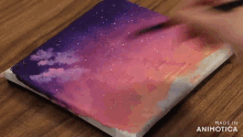 a person is painting a picture of a sunset on a canvas