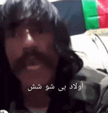 a man with long hair and a mustache is talking in a video