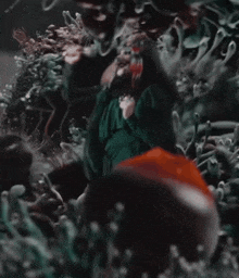 a woman in a green dress is surrounded by plants and flowers .
