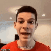 a man wearing a red shirt is making a funny face .