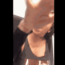 a woman in a black tank top is making a funny face .