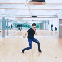 a man in a black shirt is dancing in front of a large mirror in a dance studio