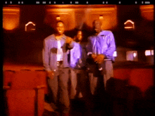 a group of men are standing in a dark room with a red seat