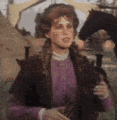 a woman in a purple dress is standing in front of a black horse .