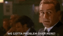 a man in a suit and tie is smoking a cigarette and saying `` we gotta problem over here ? ''