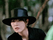 a woman wearing a black hat and a black shirt looks at the camera
