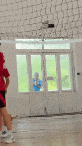 a man in a blue shirt is standing in a doorway looking out