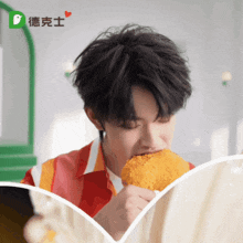 a man is eating a fried chicken wing in front of a sign that has the letter d on it