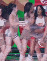 a group of women are dancing on a stage in front of a coca cola sign .