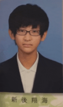 a young man wearing glasses and a suit has chinese writing on the bottom right