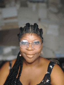 a woman wearing glasses and a braided headband smiles for the camera