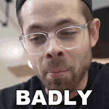 a man with glasses and a beard has the word badly above his face