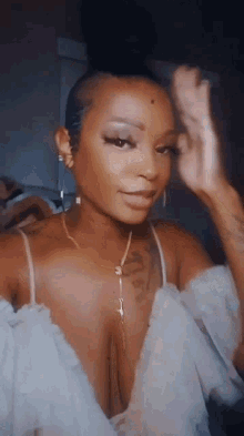 a woman with a tattoo on her arm is wearing a very revealing top and earrings .