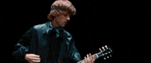 a man playing a guitar with a black background